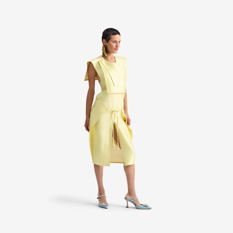 Caterpillar Dress Creamy yellow - This straight-cut midi dress features a clean silhouette with a round neckline and structured rectangular chest panels that add architectural depth.